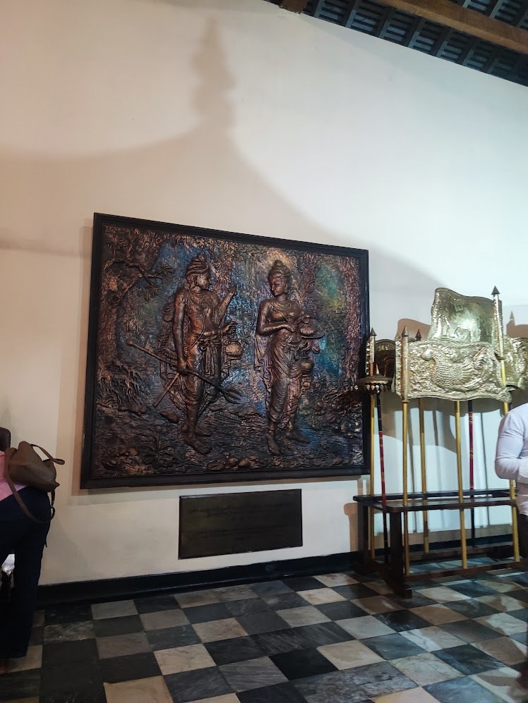 A framed bronze relief beside a ceremonial display in a gallery