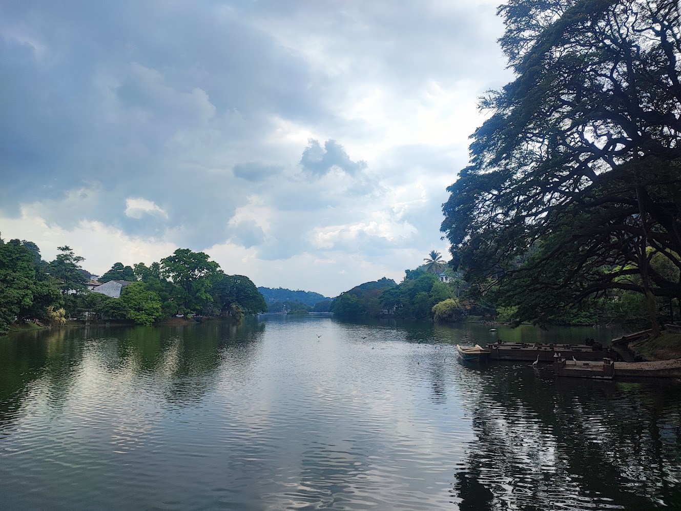 A calm lake lined by trees with small boats near the shore