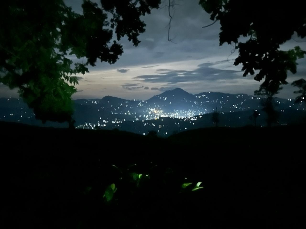 Distant town lights across dark mountain slopes at dusk