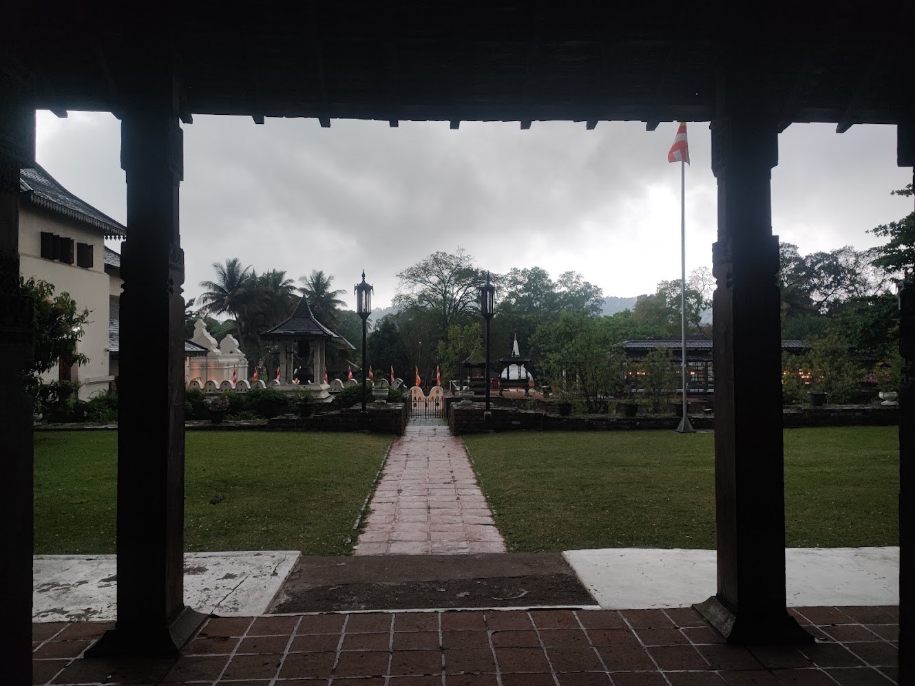 A temple courtyard framed by dark wooden pillars after rain